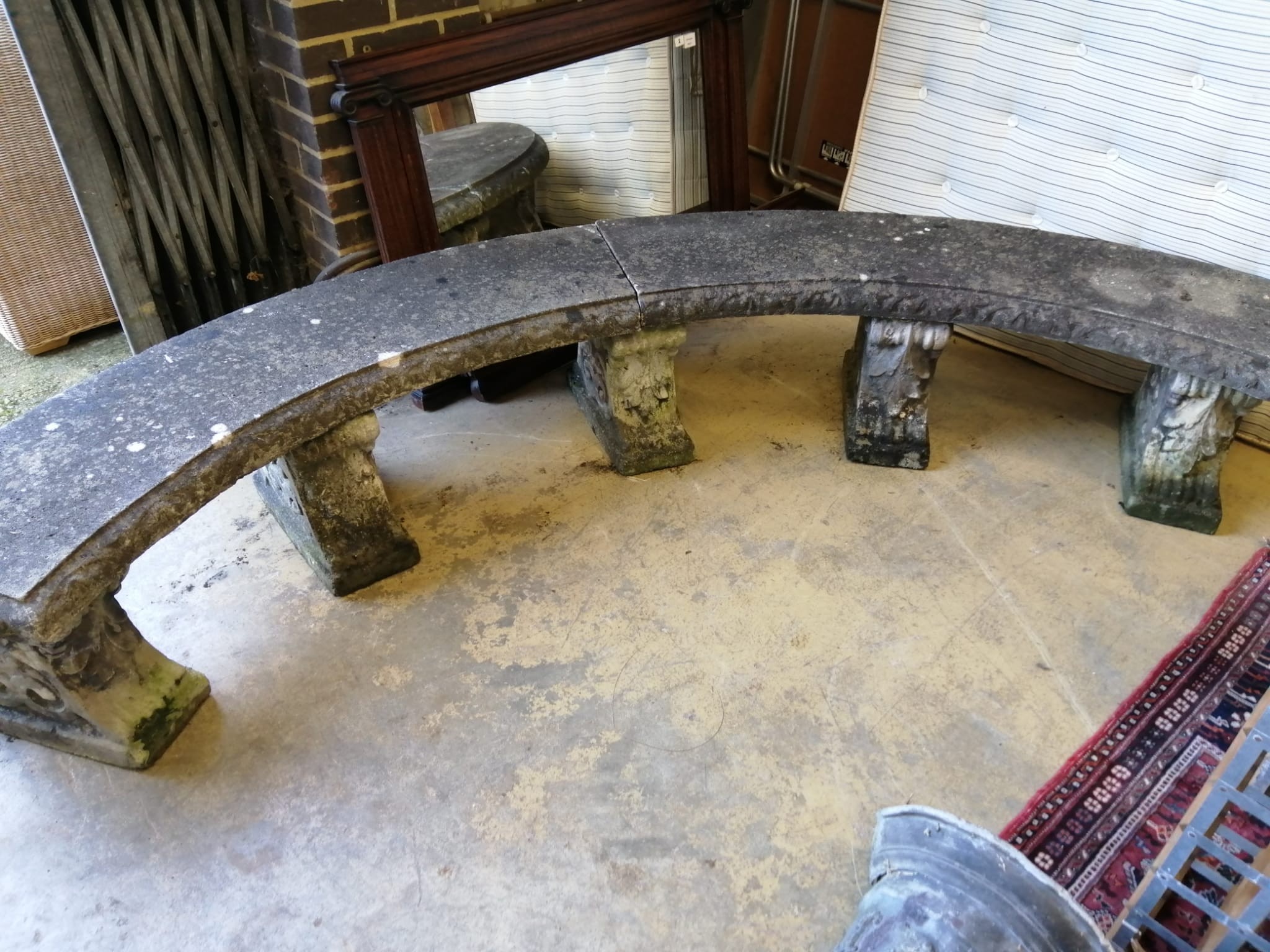 A reconstituted stone curved garden bench on five scroll supports, length 280cm, height 44cm